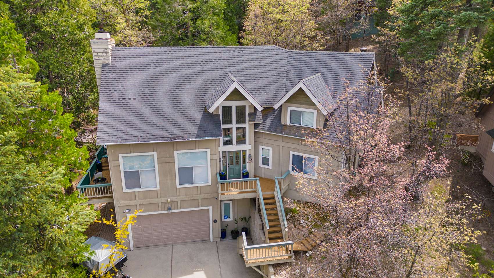 Aerial view of a mountain home among pines, shot from above the ridge.